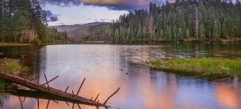 Blue sky and colorful clouds reflect off Christmas Tree Lake in Arizona's White Mountains. By Jack Dykinga