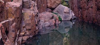 Placid water in Hell’s Half Acre Canyon reflects the sheer walls and box elders. By Jack Dykinga