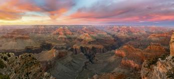 The setting sun colors the sky over the layered buttes of the Grand Canyon, as seen from the South Rim. Frequent visitors recommend arriving at the rim an hour before sundown to fully experience a sunset at the Canyon. By Adam Schallau