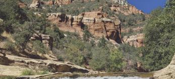 The clear water of Oak Creek tumbles over a small waterfall in the Slide Rock area of Oak Creek Canyon, near Sedona. At the time this photo was made, the Slide Rock area had not yet become an Arizona state park; it received that designation in 1987. By Josef Muench