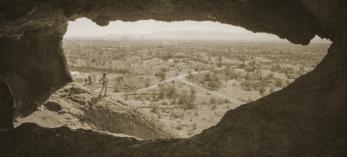 A hiker admires the view from Hole-in-the-Rock, the centerpiece of present-day Papago Park in Phoenix and Tempe, in an undated postcard photo. The site became Papago Saguaro National Monument in 1914, but it lost that designation less than two decades later. | Phoenix Public Library