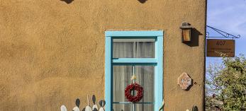 A building in Tucson's El Presidio barrio shows off a brightly-painted window frame flanked by two large light green ceramic pots housing prickly pear cactus. By Steven Meckler