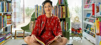 Cheron Taylor sits on a play rug in front of a bookshelf shaped like a dinosaur in the kid's section of Desierto Books in Tucson. | Steven Meckler