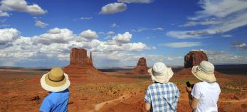Three Japanese tourists take in a view of The Mittens in Monument Valley. By Marie Baronnet