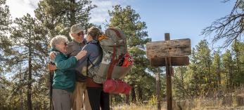 Arizona Trail thru-hiker Melina Keil, visiting from Germany, embraces “trail angels” Melody and Tim Varner on the trail near Flagstaff. Keil reached out to the Varners just a day before she was to arrive, and the couple sprang into action. | Dawn Kish
