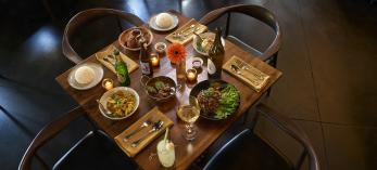 A table for four is set with bar drinks and entreés including salad, pasta and meat dishes. | David Zickl